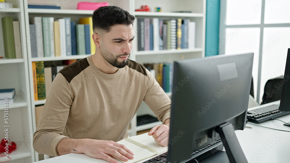 Young arab man student using computer studying with doubt expression at ...