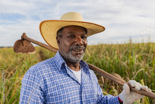 Obraz na plátně Black farmer smiling, with a hoe in his hands