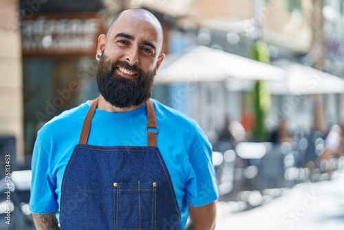 Young bald man waiter smiling confident standing at coffee shop terrace