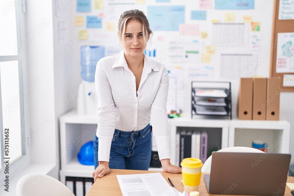 Young blonde woman business worker smiling confident standing by desk at office