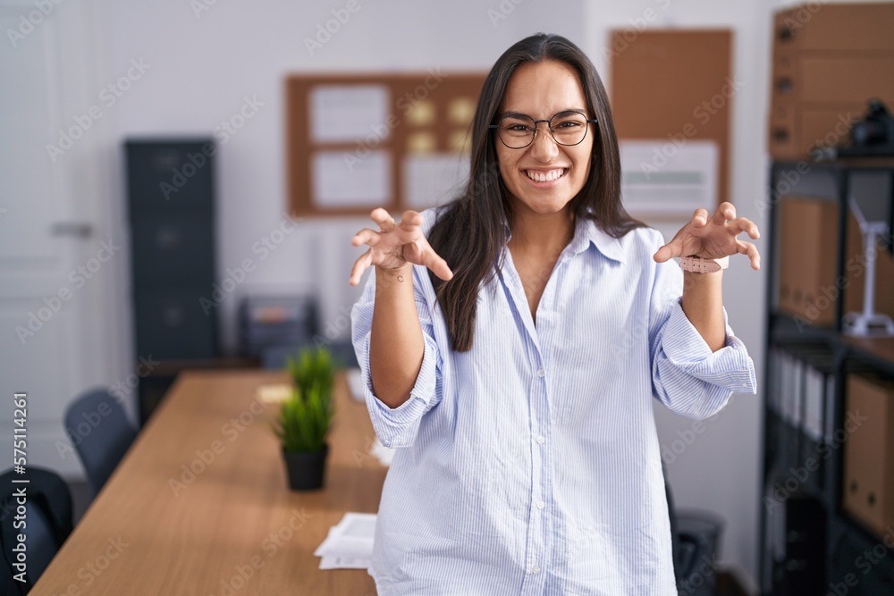Young hispanic woman at the office smiling funny doing claw gesture as cat, aggressive and sexy expression Young hispanic woman at the office smiling funny doing claw gesture as cat, aggressive and sexy expression