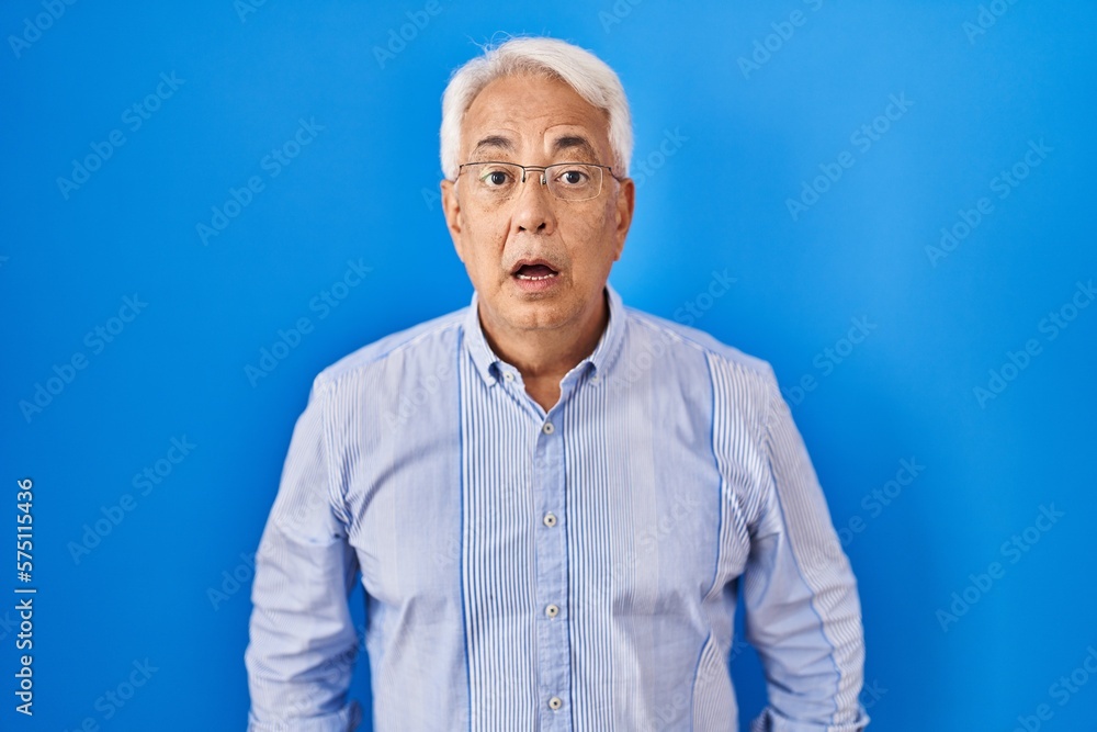 Hispanic senior man wearing glasses afraid and shocked with surprise and amazed expression, fear and excited face. Hispanic senior man wearing glasses afraid and shocked with surprise and amazed expression, fear and excited face.