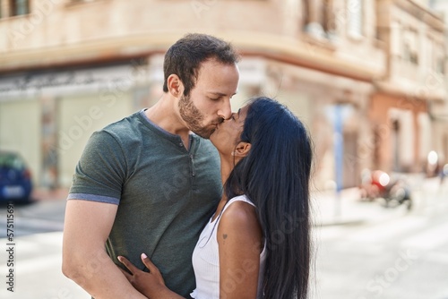 Man and woman interracial couple hugging each other and kissing at street