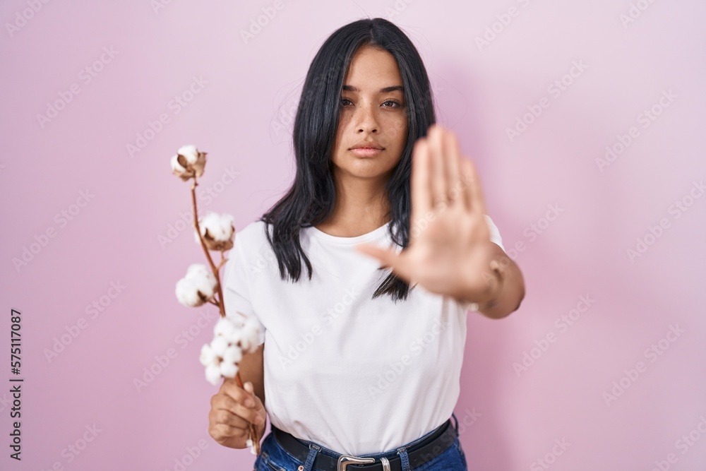 Brunette woman standing over pink background doing stop sing with palm of the hand. warning expression with negative and serious gesture on the face. Brunette woman standing over pink background doing stop sing with palm of the hand. warning expression with negative and serious gesture on the face.