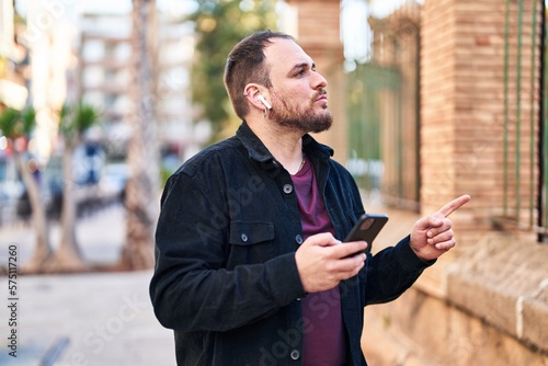 Young hispanic man listening to music and dancing at street