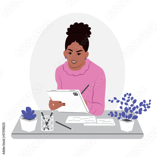 A young smiling African American woman is working on a tablet. An accountant works in finance. A beautiful business lady is working at the office desk.