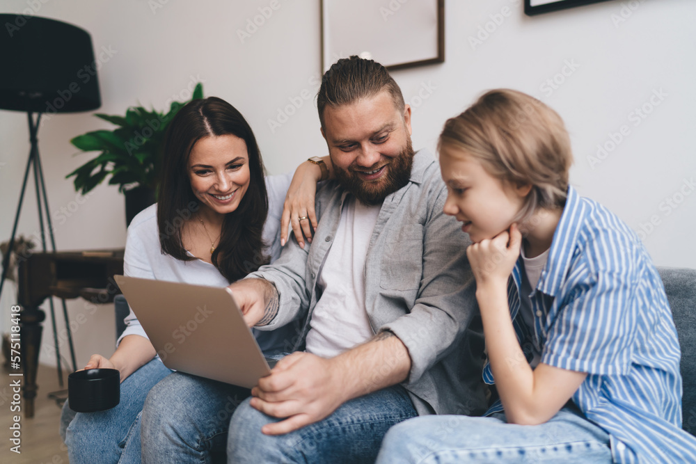 Happy family resting on couch watching photos on computer Happy family resting on couch watching photos on computer