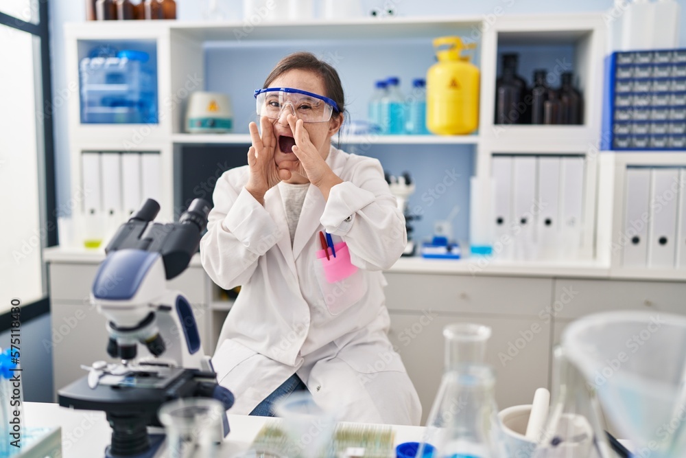 Hispanic girl with down syndrome working at scientist laboratory shouting angry out loud with hands over mouth Hispanic girl with down syndrome working at scientist laboratory shouting angry out loud with hands over mouth