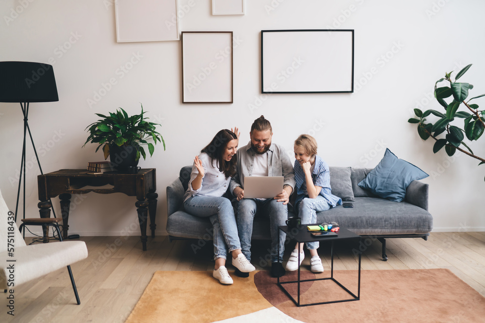 Happy family having video conversation on laptop in living room Happy family having video conversation on laptop in living room