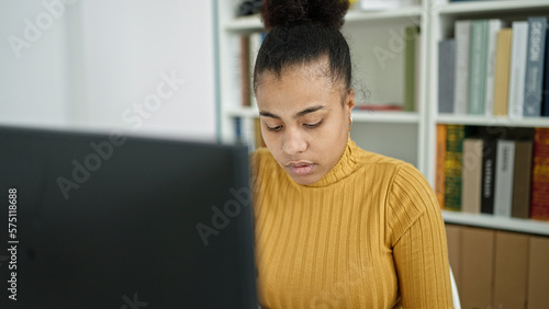 Young african american woman student using computer studying at the library