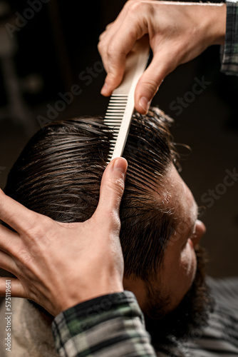 close-up view of male head with wet hair and hand of barber gently combing hair © fesenko
