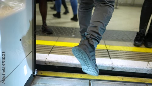 Close up person legs exiting subway train. Crowd of people commuting in underground transportation stepping out of wagon into platform