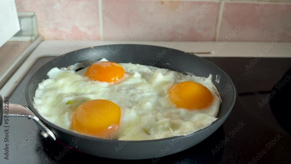 Three scrambled eggs in frying pan cooking on induction hob Three scrambled eggs in frying pan cooking on induction hob