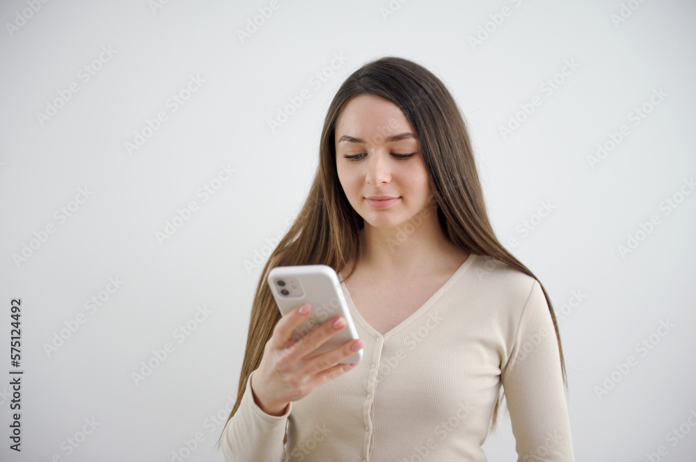 Happy portrait beautiful cute young woman smiling excited, girl typing text message on smart mobile phone enjoys online communication isolated, studio shot on white background with copy space Happy portrait beautiful cute young woman smiling excited, girl typing text message on smart mobile phone enjoys online communication isolated, studio shot on white background with copy space