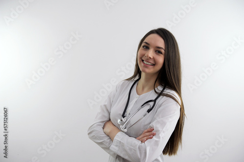 Look over there Beautiful caucasian doctor woman pointing away and smiling to you while standing against grey background. High quality photo