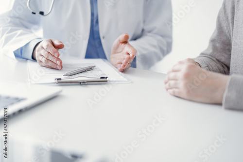 Doctor and patient discussing current health questions while sitting at the table in clinic office  only hands closeup. Medicine concept