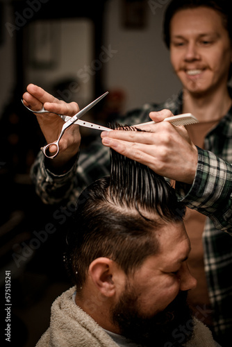close-up of hands of barber holding strand of hair and scissors and gently do haircut