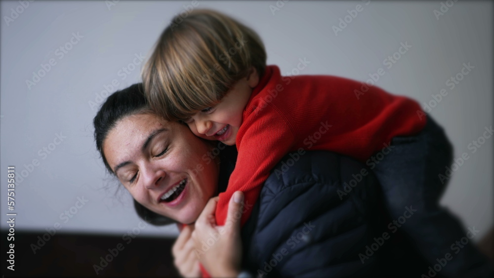 Candid mother and child embrace at home. Little boy hugging mom back Candid mother and child embrace at home. Little boy hugging mom back