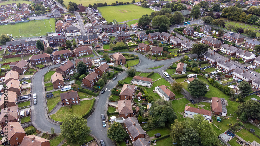 Aerial drone photo of the village of Sharlston and Sharlston Common in Wakefield in the UK, showing the residential housing estates of the village on a sunny day in the summer time.