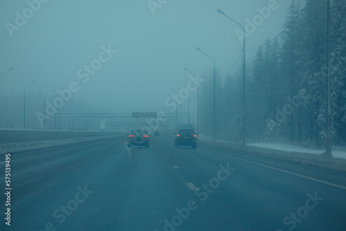 Cars are driving on the road in heavy fog. Fog on the motorway in winter.Poor visibility conditions on the highway.