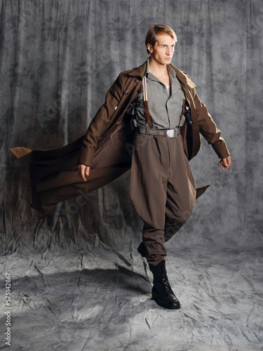 Tableau sur toile hero in a military style with a gun in his hands, a young man in a long brown coat and breeches with suspenders