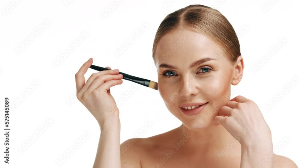 Lovely woman smiles and holds a make-up brush near her face. Natural makeup. Professional make-up artist. Lovely woman smiles and holds a make-up brush near her face. Natural makeup. Professional make-up artist.