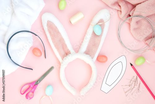 Easter flat lay. element of festive costume is hair band of ears of Easter bunny made of faux fur. Supplies needed to make craft. Layout on pink background. Top view. DIY