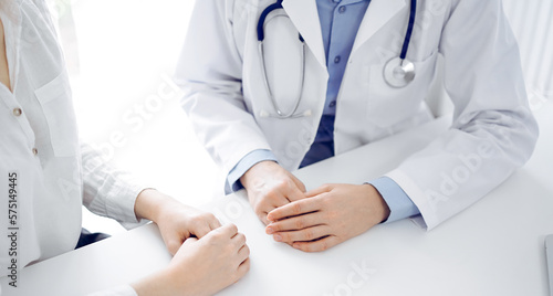 Doctor and patient discussing current health questions while sitting near of each other at the table in clinic  just hands closeup. Medicine concept