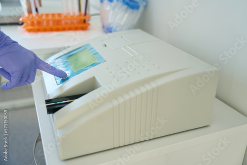 Laboratory assistant in testing unit presses button of urine analyzer