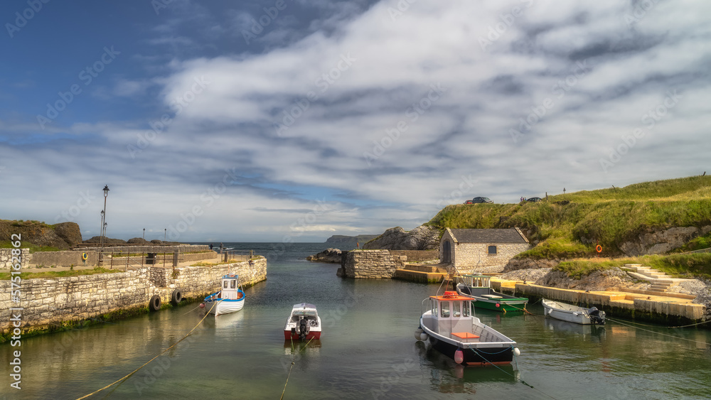 Obraz premium Beautiful small Ballintoy Harbour with stone pier and moored boats on Causeway Coast, County Antrim, Northern Ireland