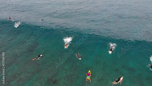 Tilt Up Shot Of Male Tourists Swimming With Surfboards On Waves In Sea - Thulusdhoo, Maldives photo