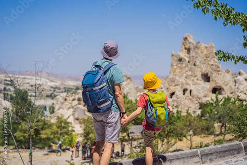 Father and son tourists exploring valley with rock formations and fairy caves near Goreme in Cappadocia Turkey