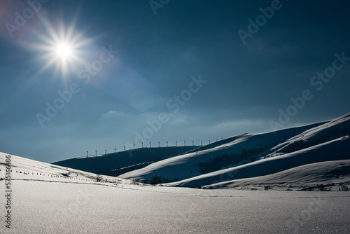 Wind farm along the horizon in snow. 