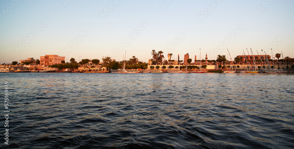 View from the river Nile to the Shore of Luxor in golden hour with Karnak temple in the background