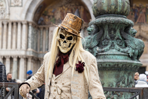 Venice, Veneto, Italy - Feb 19, 2023: Masquerade man in a costume of skull wearing a top hat and a suit at San Marco Square during 2023 Venice Carnival celebrations