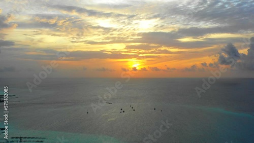 Aerial Shot Of Scenery Of Boats Moored On Tranquil Seascape, Drone Flying Over Waves During Sunset - Thulusdhoo, Maldives photo