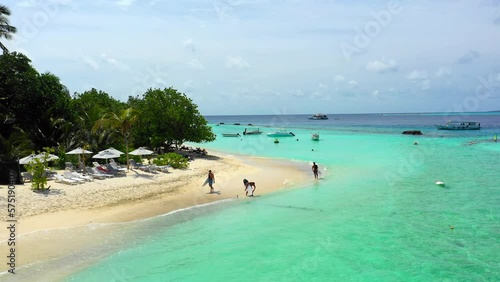 Aerial: Drone Backward Shot Of Male Surfers Walking With Surfboards At Beach On Sunny Day During Vacation - Thulusdhoo, Maldives photo