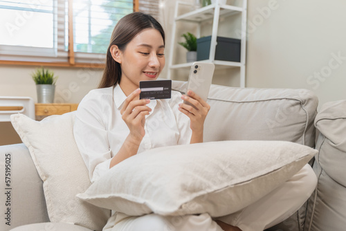 Happy Asian young woman using mobile phone shopping online and pay via credit card to get cashback bonus.