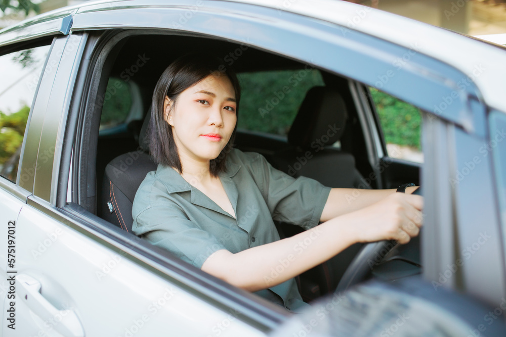Close up portrait of pleasant looking female with glad positive expression, being satisfied with unforgettable journey by car, sits on driver`s seat, enjoys music. People, driving, transport concept