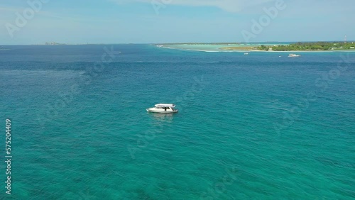 Aerial Panning Shot Of White Boat Moving On Wavy Ocean, Drone Flying Forward During Sunny Day - Thulusdhoo, Maldives photo