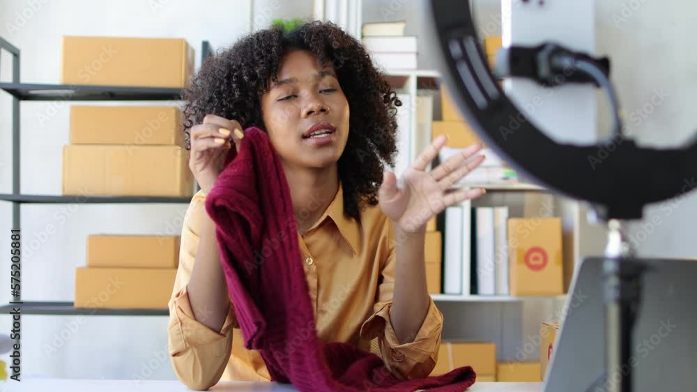 African female designer working in design studio going live to sell her clothes and products. African female designer working in design studio going live to sell her clothes and products.