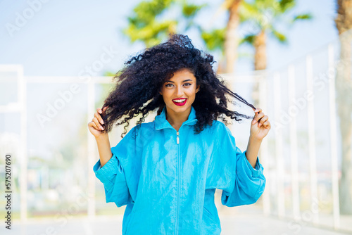 Obraz na plátně multicultural race woman with curl hair in blue windbreaker outdoor