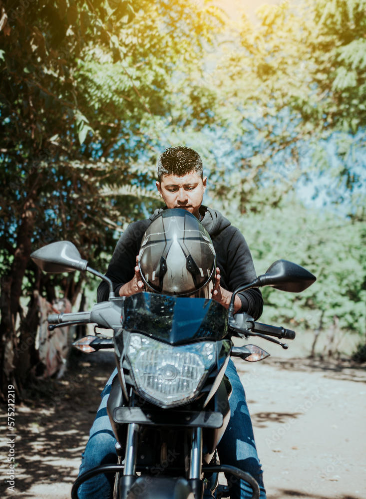 Motorcyclist putting on safety helmet, Biker motorcycle safety concept. Young motorcyclist man putting on safety helmet, Man on motorcycle putting on helmet