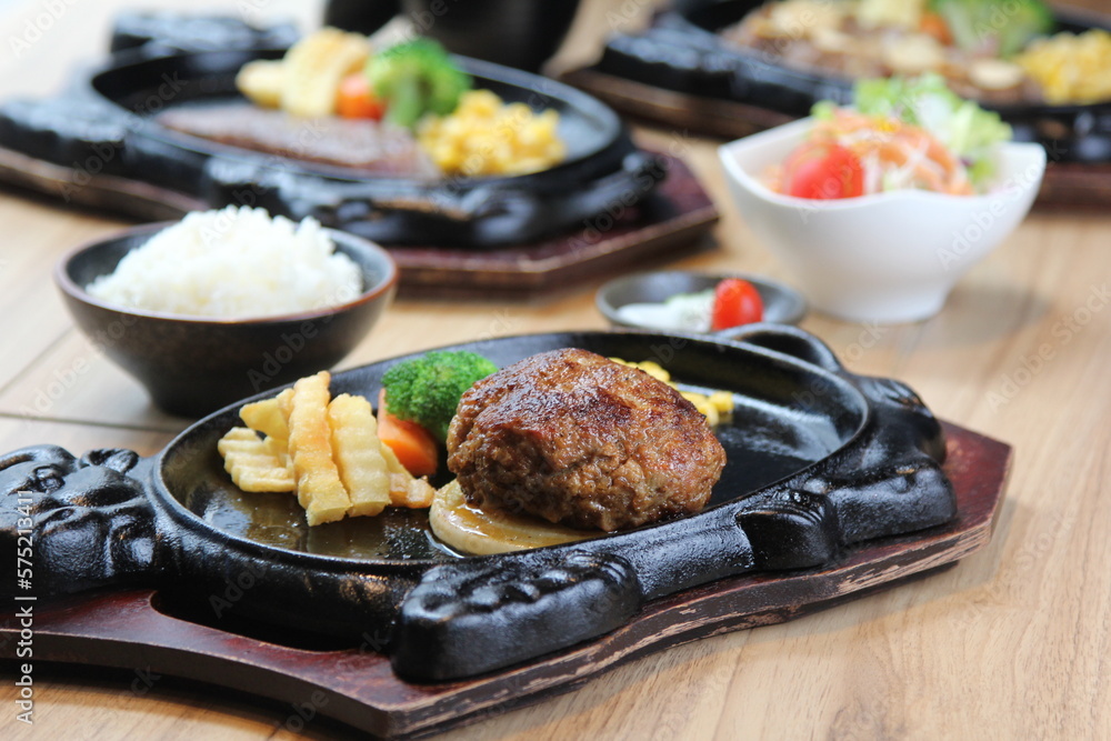 Japanese Hamburg steak with brown sauce and vegetables on a black hot plate in a Japanese restaurant Japanese Hamburg steak with brown sauce and vegetables on a black hot plate in a Japanese restaurant