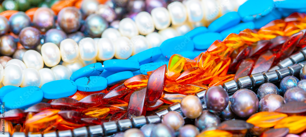 Beads and necklaces made of colored semi precious stones. Background from a variety of beautiful jewelry, multi-colored turquoise stones, amber, cat's eye, pearls.