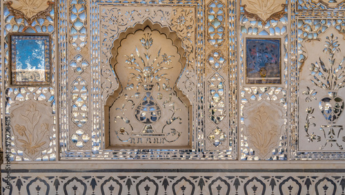 A fragment of the design of the Mirror Palace in the ancient Amber Fort. Patterns and floral ornaments from pieces of mirrors are laid out on the wall. Relief carving. India. Jaipur