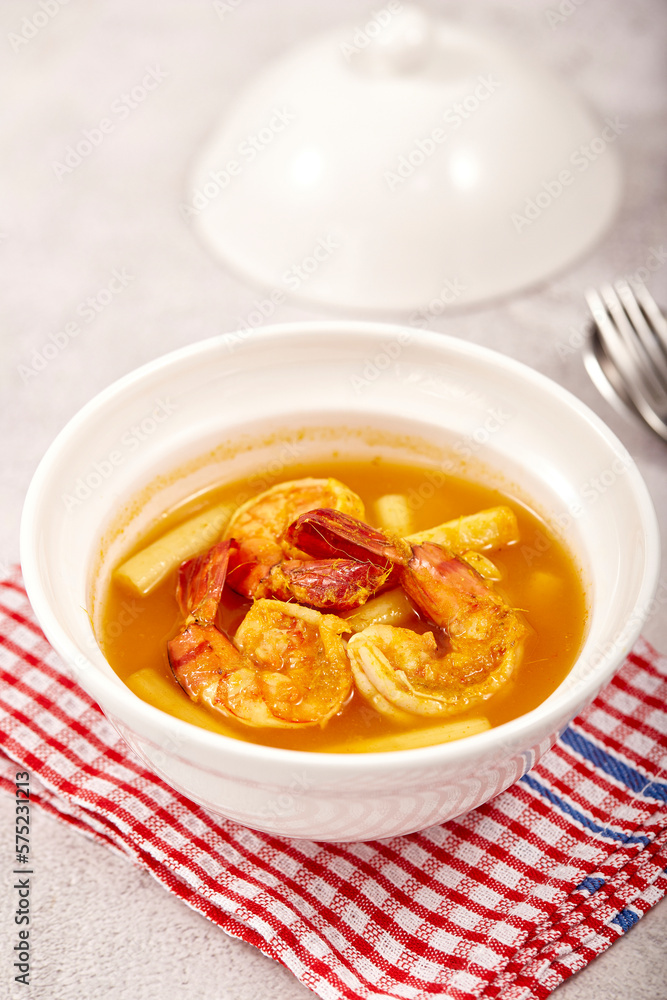 Sour soup with lotus stem and shrimps in a white bowl on table. local food of Thailand. Sour soup with lotus stem and shrimps in a white bowl on table. local food of Thailand.
