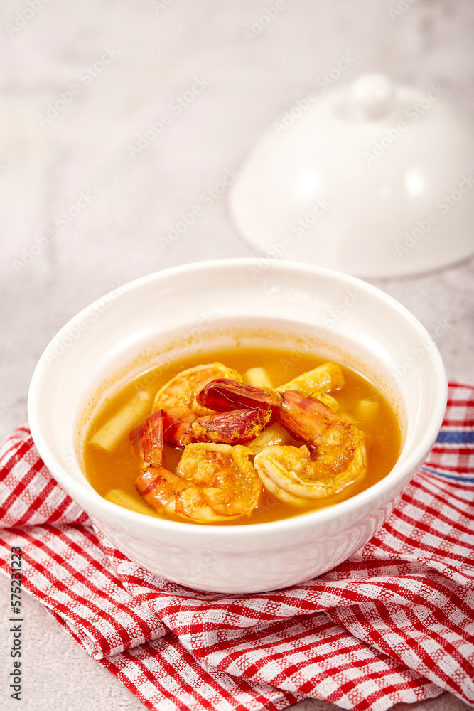 Sour soup with lotus stem and shrimps in a white bowl on table. local food of Thailand. Sour soup with lotus stem and shrimps in a white bowl on table. local food of Thailand.