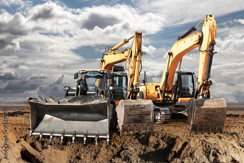 Schilderij op canvas Bulldozer or loader moves the earth at the construction site against the blue sky