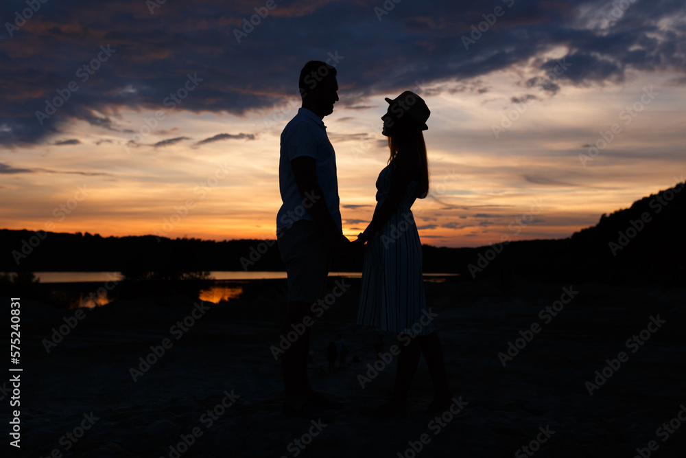 Couple standing holding hands at summer sunset
